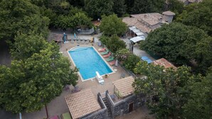 Vista aerea di un resort con piscina circondata da lettini e un edificio in pietra.