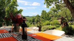 An outdoor dining area with a wooden table, wine glasses, and a bottle of wine. - Typical Tuscan farmhouse in charming position between Panzano -Greve in Chianti  (Greve in Chianti)