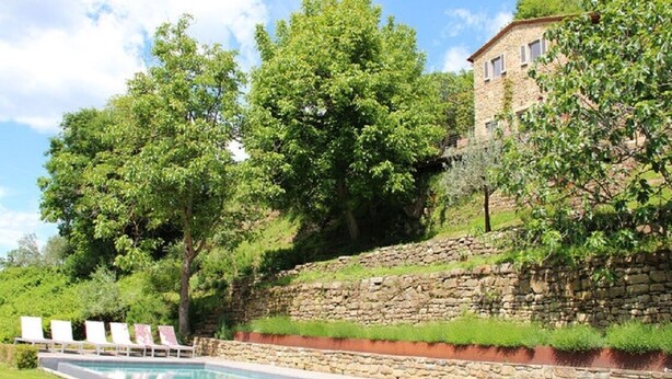 A pool with lounge chairs, a stone wall, and a building with a stone facade. - Typical Tuscan farmhouse in charming position between Panzano -Greve in Chianti  (Greve in Chianti)