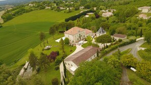 Un vaste domaine comprenant plusieurs bâtiments, de vastes étendues de verdure et une maison principale dotée d’un toit imposant.