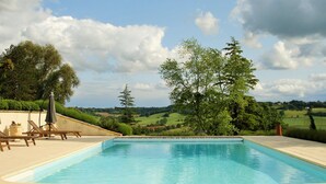 Una piscina rectangular con superficie de agua azul cristalina, rodeada por una terraza de color claro.