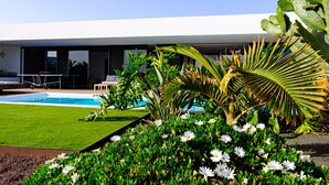 Ein modernes Hotel mit Schwimmbad, üppiger Bepflanzung und freiem Blick auf den Poolbereich.