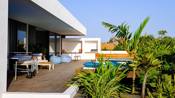 Ein moderner Außenbereich mit Pool, Holzterrasse und unterschiedlichen Sitzgelegenheiten.