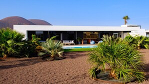 Ein modernes Haus mit Swimmingpool, umgeben von tropischen Pflanzen.
