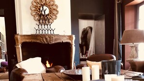 A rustic wooden table with candles and glasses, a leather sofa, a fireplace, and a decorative wall piece. - Near L'Isle-sur-la-Sorgue, quiet old Provençal Mas, 19 Pers. Swimming pool. (Le Thor)