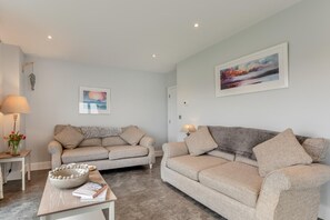 A modern living room with two sofas, a coffee table, and decorative items.