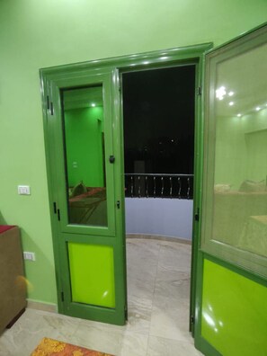 Una habitación con una puerta verde que da a un balcón con barandilla.