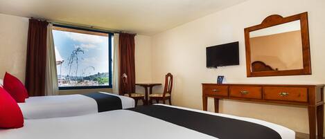 A hotel room with two beds, a desk, a chair, a TV, and a large window offering a view.