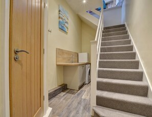 A staircase leading to a second floor, a wooden door, a small kitchen area with a sink, and a painting on the wall. - 2 Bed in Appledore (oc-hide1) (Appledore)