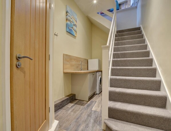 A staircase leading to a second floor, a wooden door, a small kitchen area with a sink, and a painting on the wall. - 2 Bed in Appledore (oc-hide1) (Appledore)