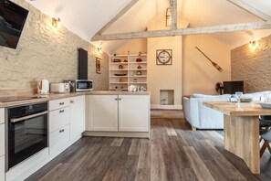 A compact kitchen with modern appliances, a dining area with a wooden table, and a cozy seating arrangement.