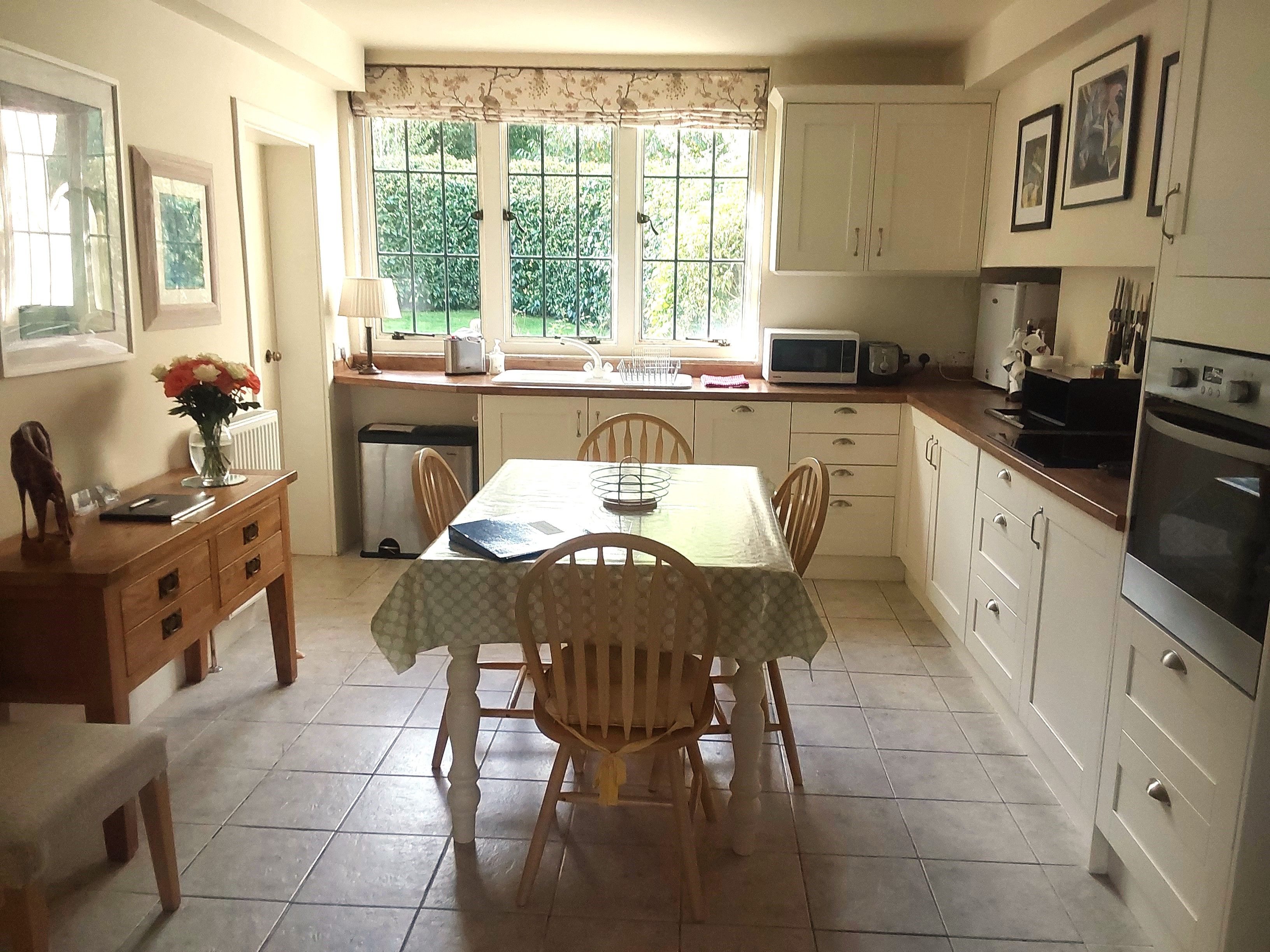 A kitchen with a dining table, chairs, cabinets, a microwave, and an oven.