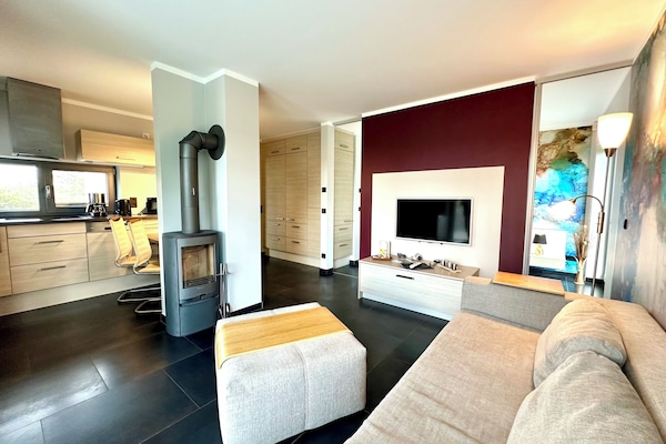 Wohnzimmer mit Kamin und offener Küche – Mittelpunkt der Ferienwohnung