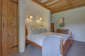 A bedroom with a wooden bed, two wall-mounted lamps, a dresser, and a mirror.