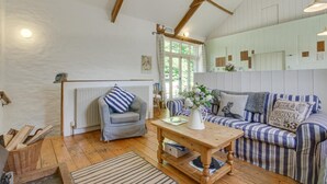 A cozy room with a wooden floor, a striped sofa, a chair, a table with a vase, and a radiator. - 3 Bed in Parracombe (oc-molec) (Parracombe)