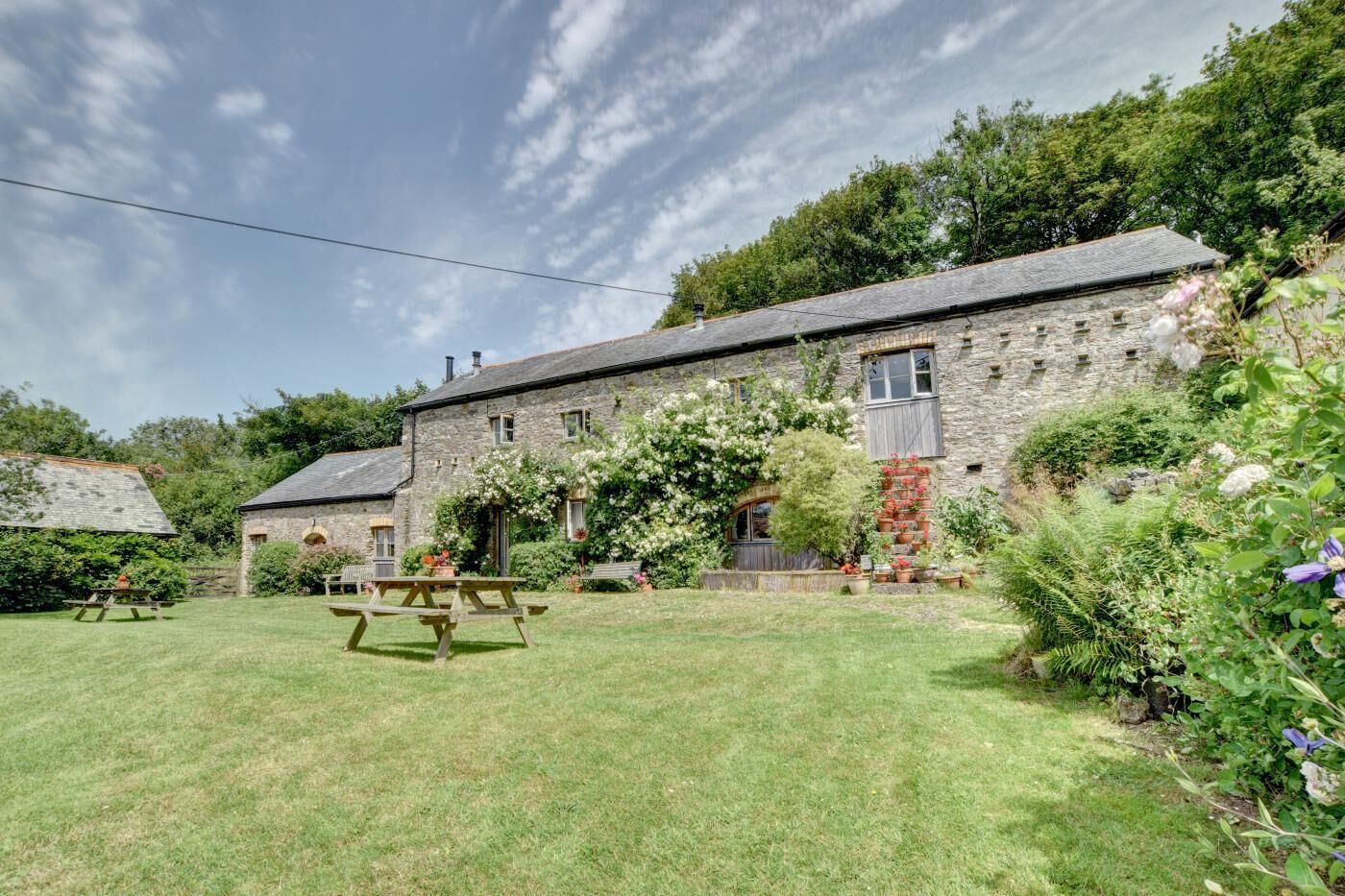 A stone building with a garden, picnic table, and a stone wall.