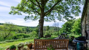 A bench, a picnic table, and potted plants in a garden with a view of a green landscape. - 3 Bed in Parracombe (oc-molec) (Parracombe)