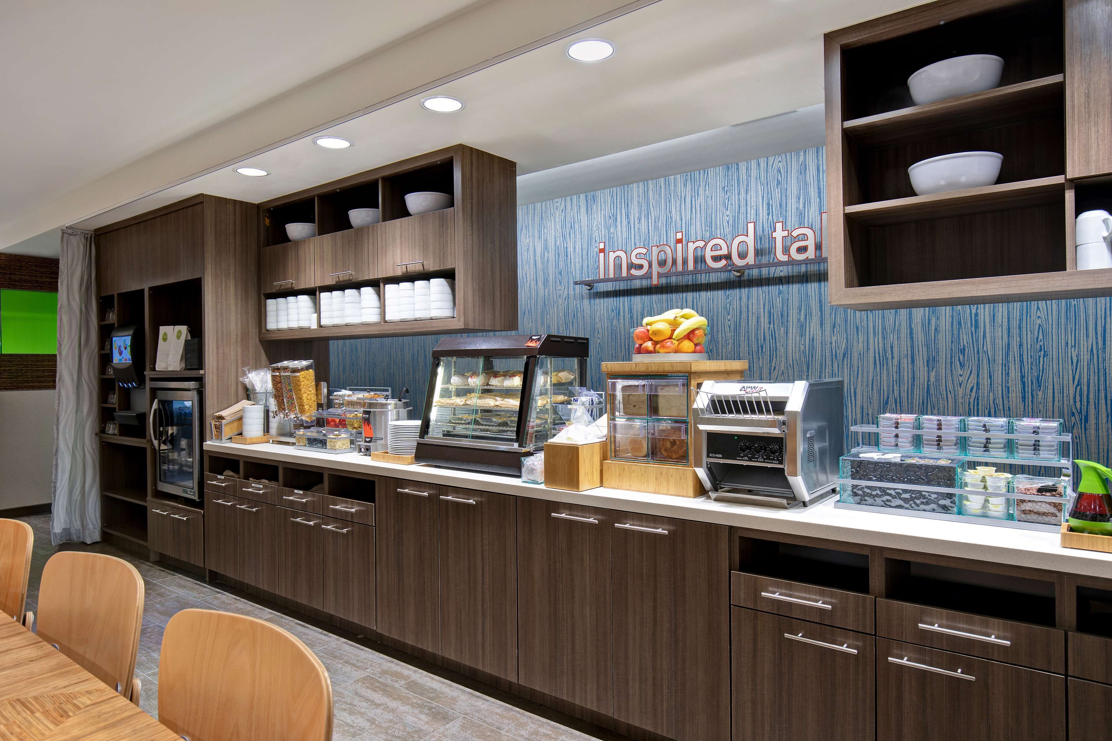 Un comptoir-bar moderne doté d’une vitrine réfrigérée, d’une machine à café et de divers produits alimentaires.