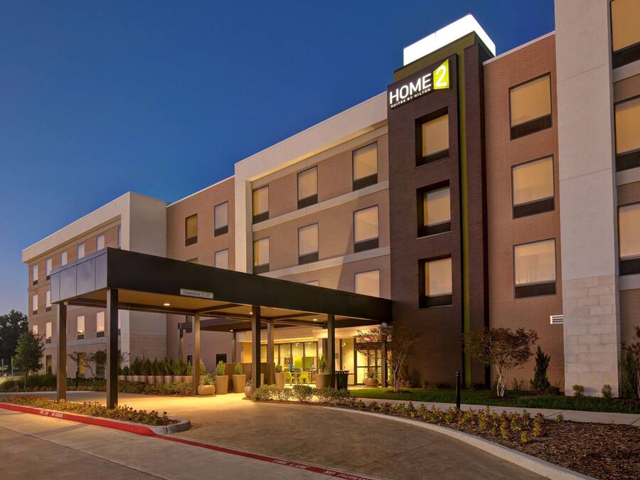 A modern hotel with a covered entrance, multiple floors, and a well-lit facade.