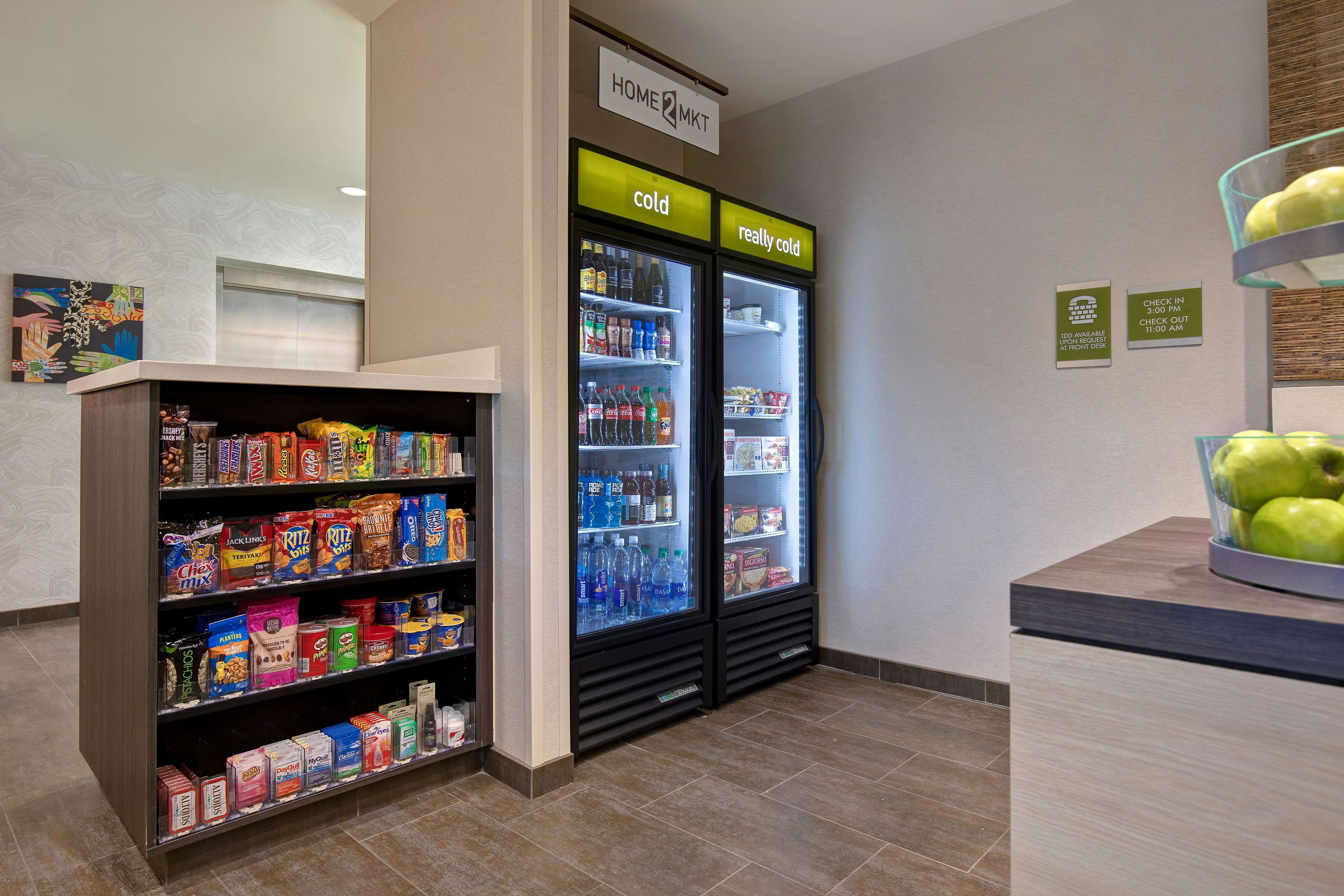 Un espace de libre-service où l'on peut se servir des boissons, avec des options de boissons réfrigérées et une étagère de collations.