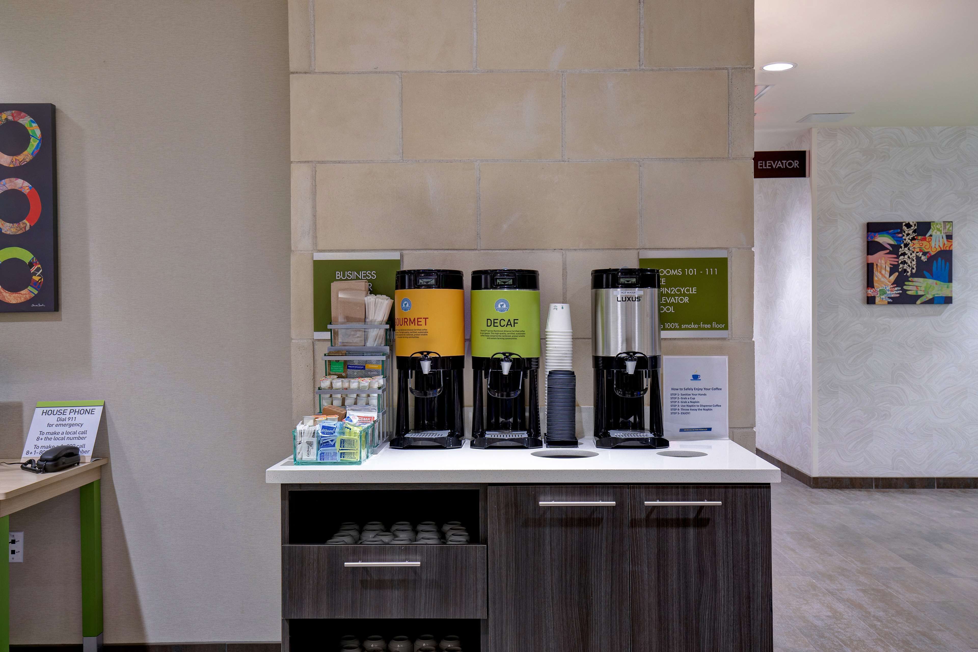 Una estación de café con varias máquinas de café y un cartel que indica la ubicación del teléfono de la casa.
