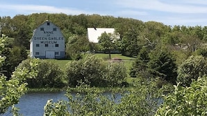Un bâtiment abritant un musée, appelé « Musée d’Anne de Green Gables », entouré de verdure et bordé par un plan d’eau.