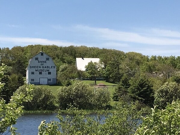 A museum building named "Anne of Green Gables Museum" surrounded by greenery and a body of water.