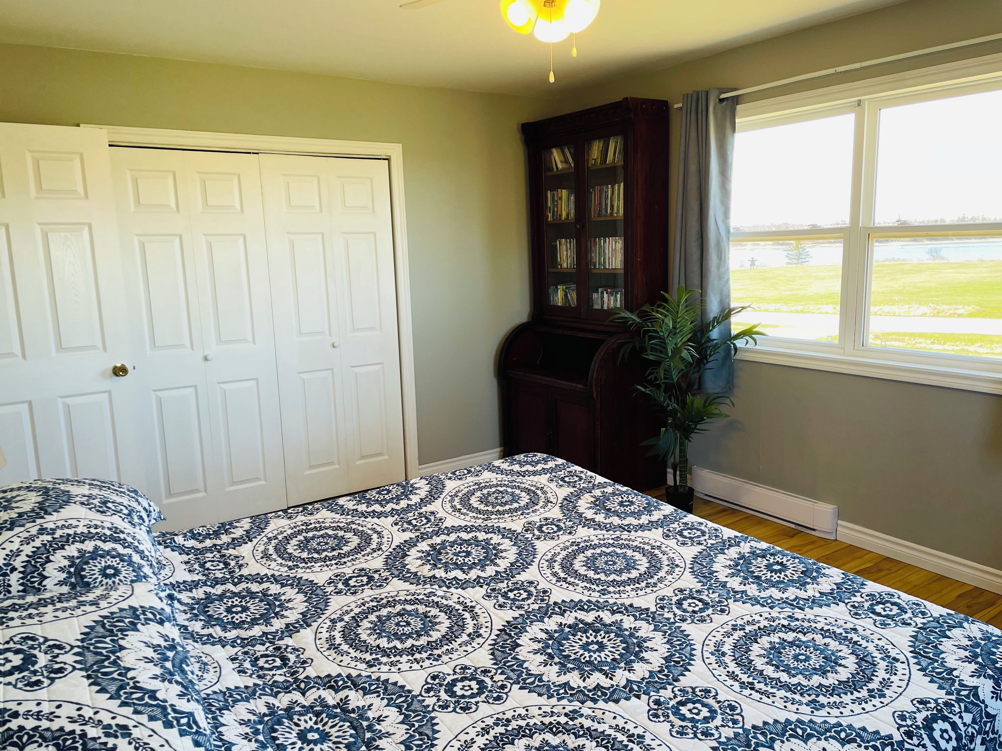 Un dormitorio con cama, armario, ventana con vistas y ventilador de techo.