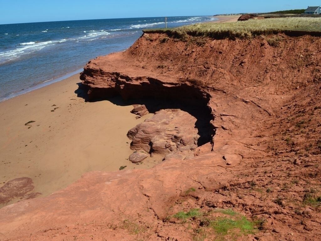 Un paisaje costero con un acantilado imponente y una playa.