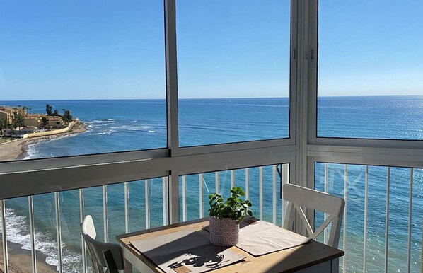 Un balcon avec vue sur l’océan et un bâtiment situé de l’autre côté de l’eau.