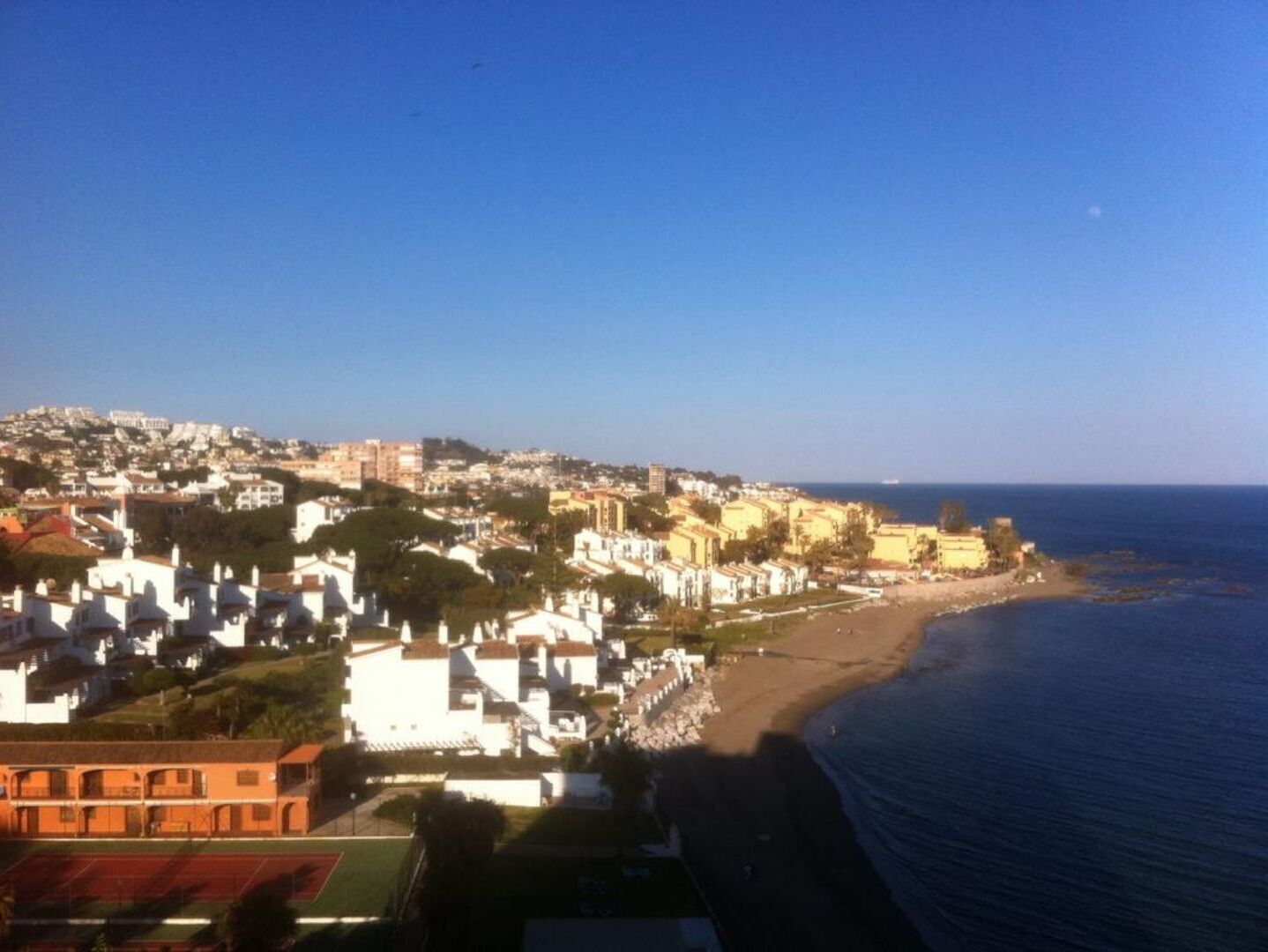 Una località costiera con spiaggia, edifici e cielo sereno.