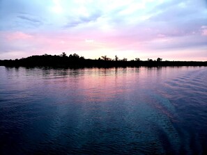 A calm lake with a silhouette of trees on the horizon and a sky with soft pink and blue hues. - Ultra Private Lake Home on Sandy Beach! (Walker)