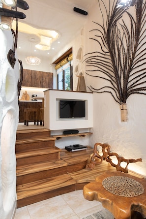 A modern interior with a wooden staircase, a flat-screen TV, and a decorative plant.