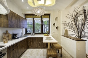 A modern kitchen with a white countertop, wooden cabinets, and a large window with a view of trees.
