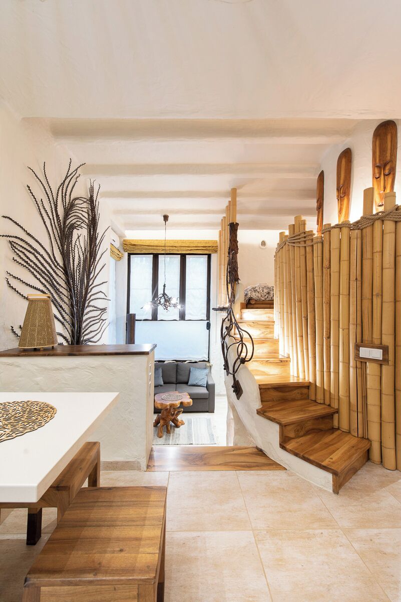 Un interior moderno con una escalera de madera, un comedor con una mesa blanca y una sala de estar con sofá.