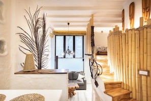 A room with a sofa, a wooden staircase, and a large plant.