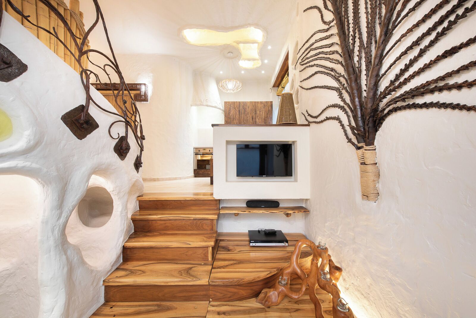 Un intérieur moderne agrémenté d’un escalier en bois, d’un téléviseur à écran plat et d’œuvres d’art décoratives murales.