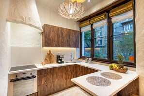 A modern kitchen with a built-in oven, a coffee machine, and a window with a view of buildings.