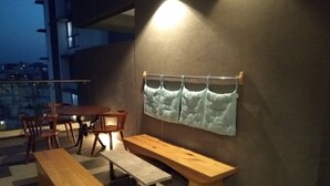 A terrace with wooden furniture, including a table and benches, and a wall-mounted cushion.