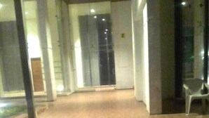 A spacious indoor area with a wooden floor, a staircase leading to an upper level, and a glass door at the far end.