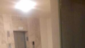 A hallway with a marble floor and a door with a sign above it.