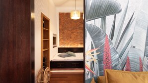 A bedroom with a wooden headboard, a bed with pillows, a hanging light fixture, and a wall with a leaf pattern. - Exotic Elegance - IR sauna, aircon, 3-bedrooms, 2 bathrooms, Wi-Fi (Krakow, malopolska)