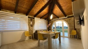 Comedor con techo de madera, paredes de piedra y vistas a través de un ventanal.