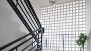 Una escalera con barandilla negra, una planta en maceta y un accesorio de iluminación decorativo.