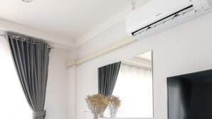 Un espacio de oficina moderno con un escritorio blanco, una silla negra, un televisor de pantalla plana y una unidad de aire acondicionado montada en la pared.