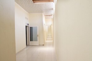 A narrow, well-lit hallway with a tiled floor and a door at the end.