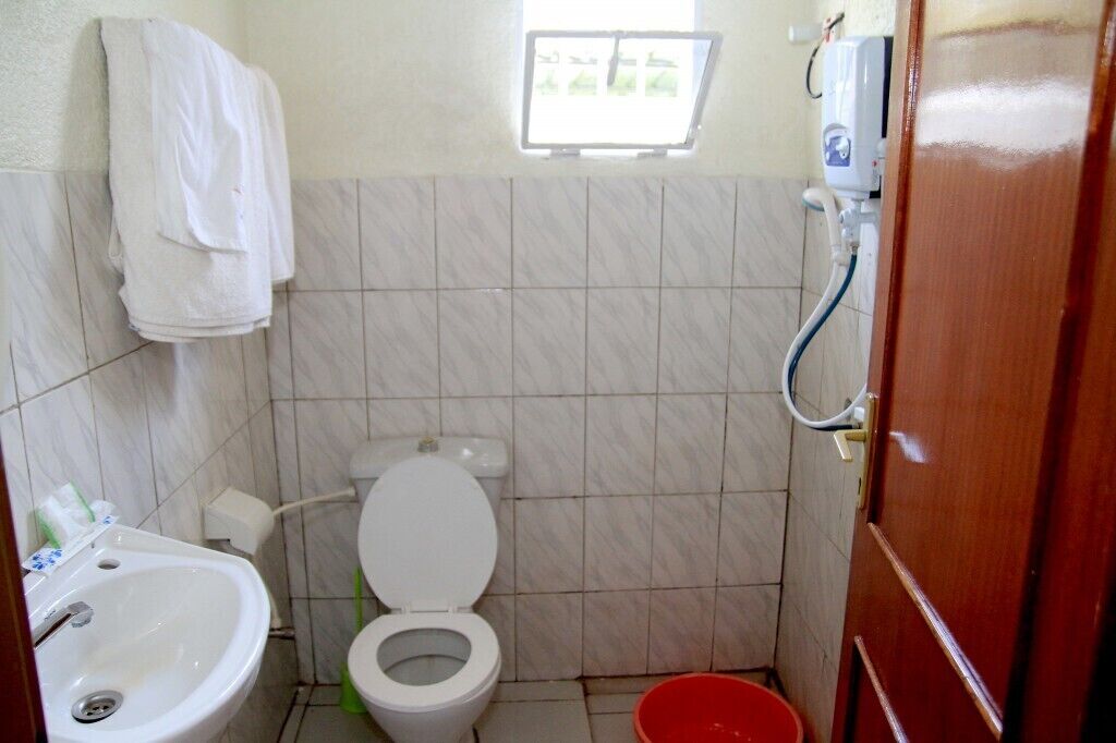 A small bathroom with a toilet, a sink, a shower, and a window.