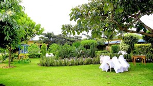 A well-maintained garden with a grassy lawn, a play area, and a table set up for an event.