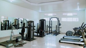 A gym with various exercise equipment, including treadmills, weight machines, and a bench press.
