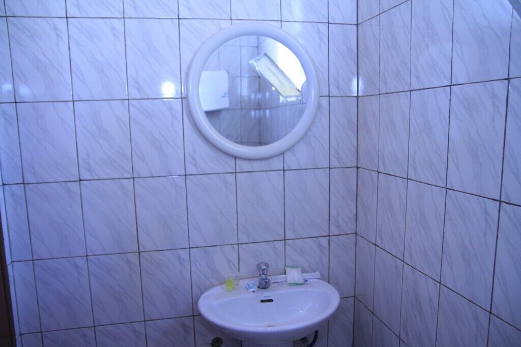 A bathroom with a white sink, a mirror, and tiled walls.